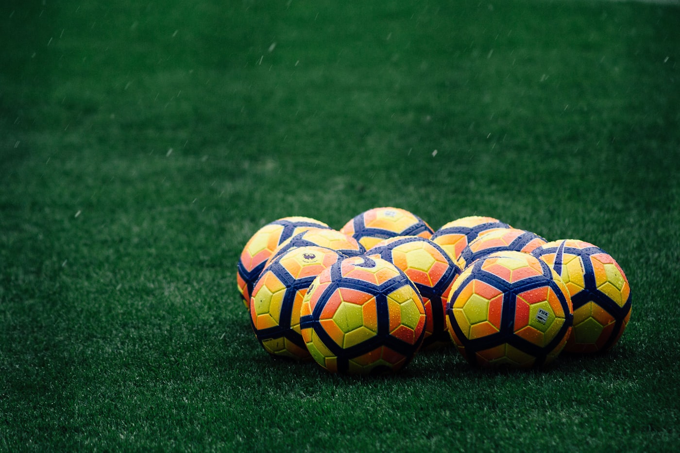 Cluster of match balls on wet grass during rainfall