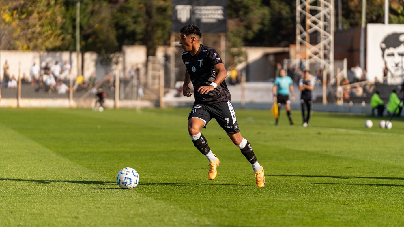 Player dribbling the ball forward during a daytime match