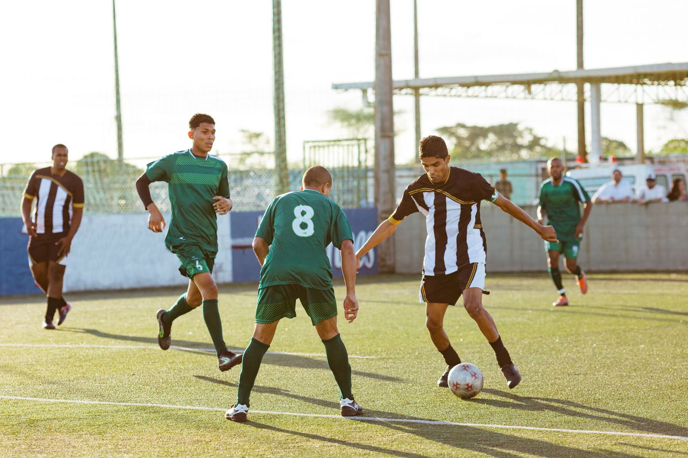 Five outfield players converging on the ball during a match
